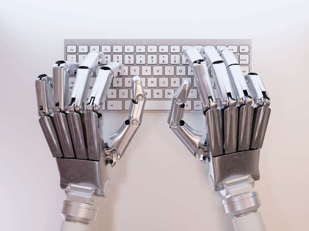 Ręce robota umieszczone na klawiaturze od komputera stacjonarnego. Czy antyplagiat wykrywa AI? 