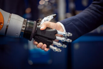 Robot i człowiek podający sobie wzajemnie ręce.